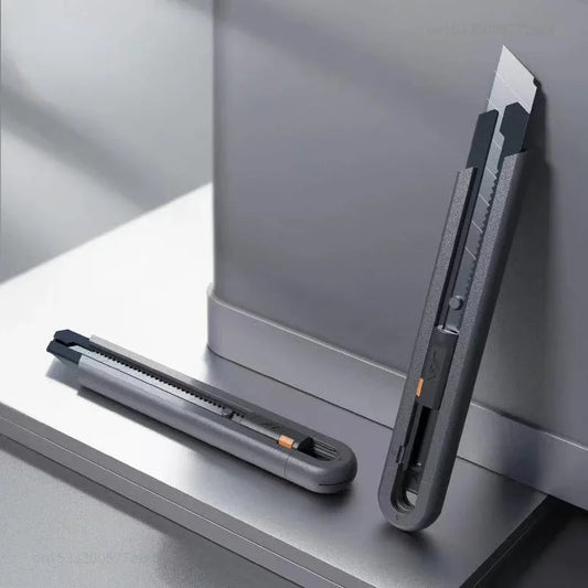 Gray utility knife on a metallic surface with a blurred background